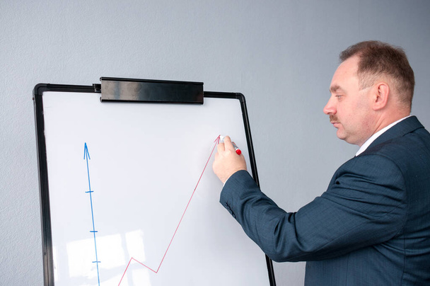 A man draws a graph of sales on the whiteboard - Foto, Imagem