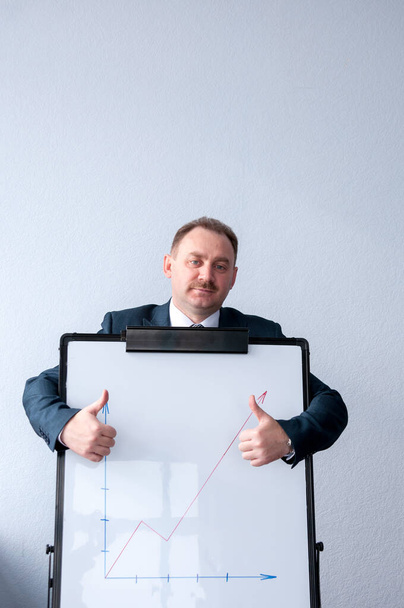 A man is standing behind the white board and holding thumbs up - Photo, Image