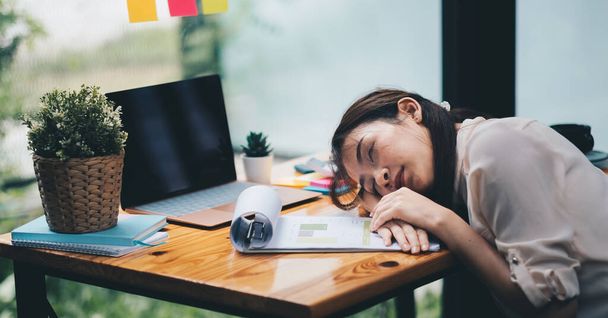 Tired and overworked business woman. Young exhausted girl sleeping on table during her work Entrepreneur, freelance worker in stress concept - Photo, Image