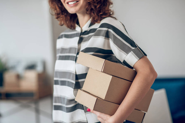 Smiling joyous female worker with packages standing insid - Foto, Bild