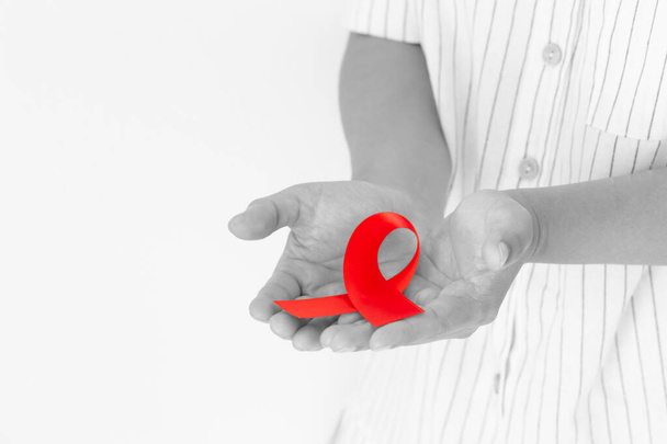 Ruce držící červenou stuhu na bílém pozadí kopírují prostor, symbol solidarity lidí žijících s HIV / AIDS a pro povědomí a prevenci zneužívání drog a řízení pod vlivem alkoholu. Zdravotní koncepce - Fotografie, Obrázek