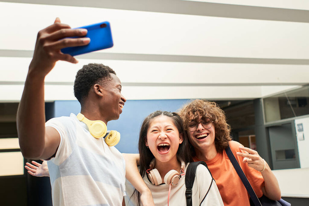 Groupe multi-ethnique d'étudiants prenant un selfie au collège. Les camarades de classe s'amusent ensemble. - Photo, image