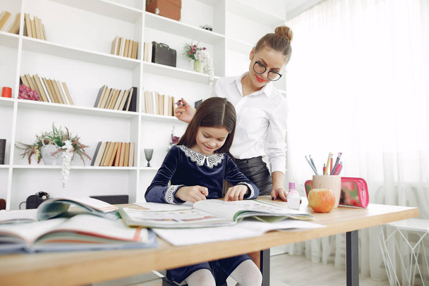 Tutor with litthe girl studying at home - Фото, изображение