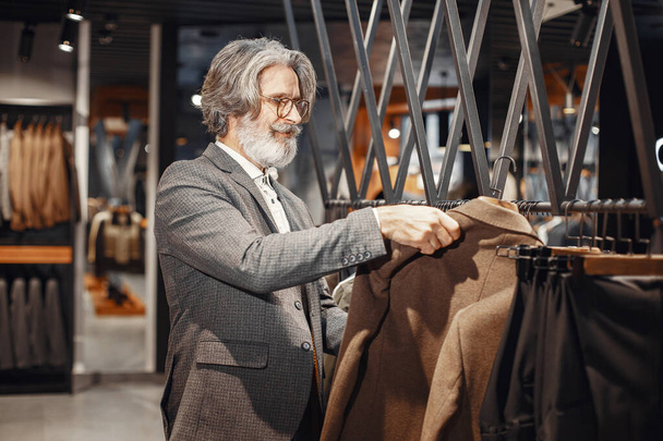 Senior man choosing a new suit in a store - Foto, imagen