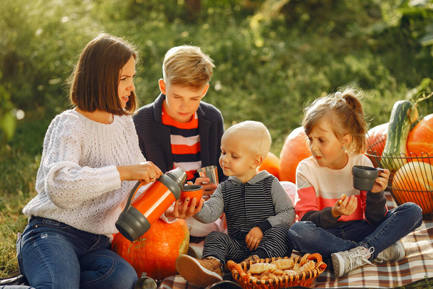 Big family sitting on a garden near many pumpkins - Foto, Bild