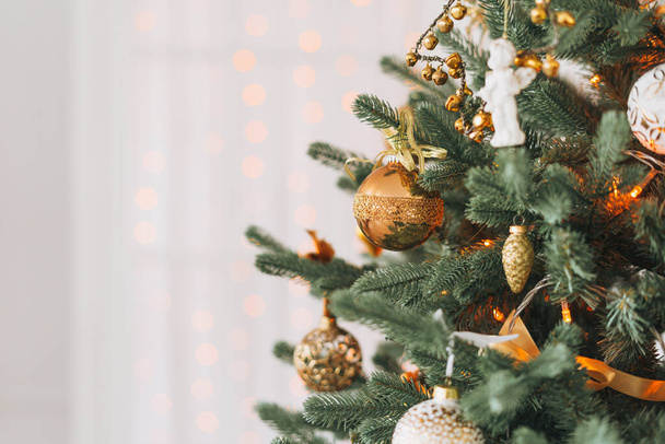 Arbre de Noël décoré en jouets dorés et blancs avec des lumières fond texturé bokeh - Photo, image