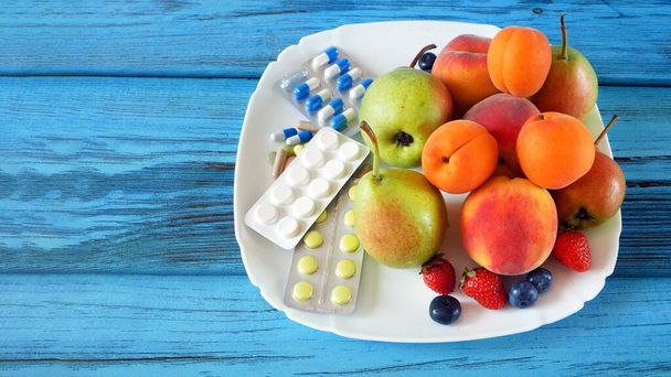tuoreita luonnollisia hedelmiä vs pillereitä. Luonnollinen vitamiini hedelmissä vs synteettinen vitamiini pillereitä kopioi tilaa. Valinta luonnollisen ja synteettisen terveydenhuollon välillä. Vaihtoehtoinen lääketiede. lähikuva-analyysi - Valokuva, kuva