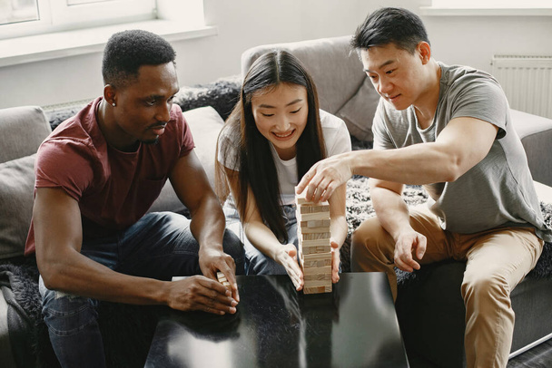 Three friends playing jenga in the living room - Foto, imagen