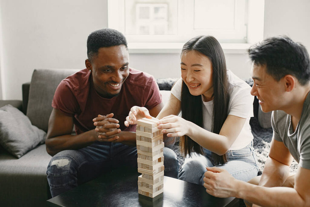 Three friends playing jenga in the living room - Foto, Imagen