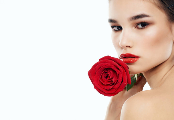 όμορφη γυναίκα γυμνούς ώμους με κόκκινο λουλούδι στο φως φόντο. Υψηλής ποιότητας φωτογραφία - Φωτογραφία, εικόνα