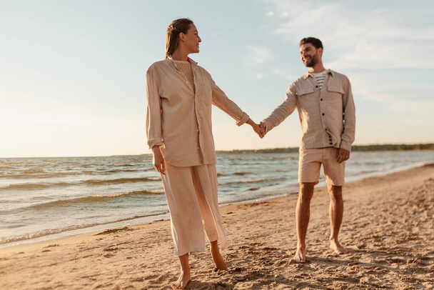 happy couple holding hands on summer beach - Zdjęcie, obraz