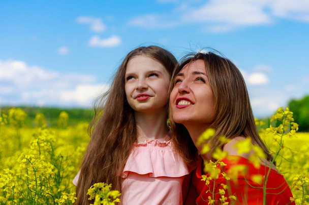 Máma a dcera v přírodě ve venkovním životním stylu. Veselá blesk žlutá barva kvetoucího řepkového pole na pozadí. Koncepce klidu. - Fotografie, Obrázek