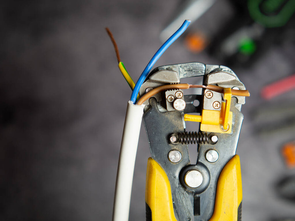 Un électricien dénude les fils électriques avec une décapeuse. - Photo, image