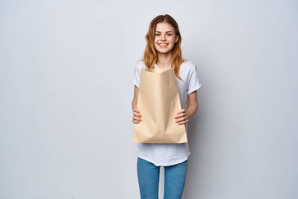 fröhliche Frau in weißem T-Shirt mit Papiereinkaufstasche - Foto, Bild