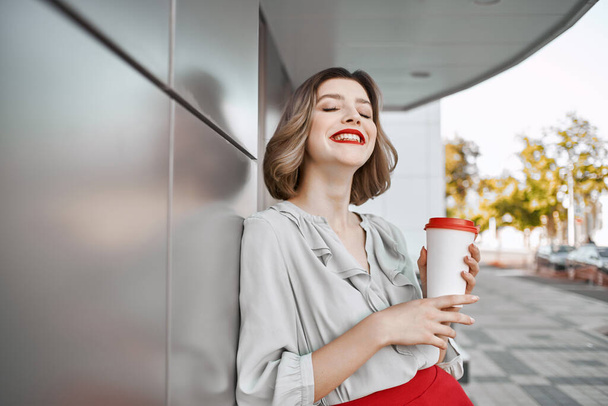 csinos nő piros szoknya kávé csésze szabadban közel épület csillogás - Fotó, kép