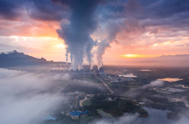 Αεροφωτογραφία σταθμός παραγωγής ενέργειας από άνθρακα στο πρωί ομίχλη, ο πρωινός ήλιος ανατέλλει. σταθμός παραγωγής ενέργειας από άνθρακα και έννοια του περιβάλλοντος. Άνθρακα και ατμού. Mae Moh, Lampang, Ταϊλάνδη. - Φωτογραφία, εικόνα