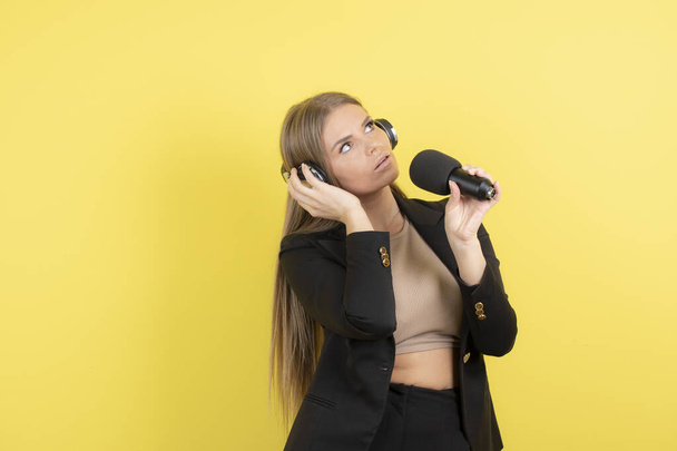 Portrait of young presenter in headphones reporting something on yellow background. High quality photo - Φωτογραφία, εικόνα