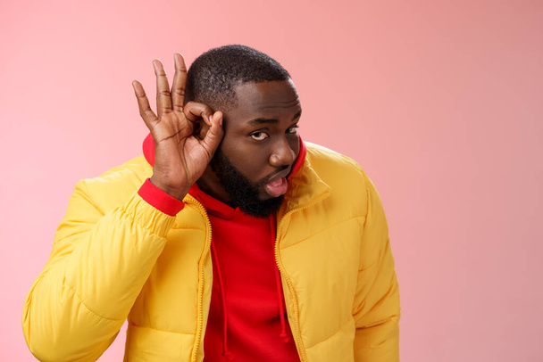 Curious funny charismatic black bearded guy bending forward hold hands ear eavesdropping wanna overhear girlfriend conversation behind door standing curious gossiping pink background - Photo, Image