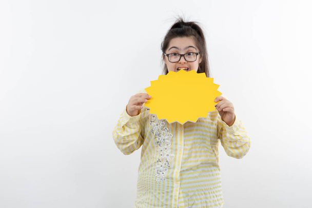 Down sendromlu kız sarı güneş figürlü kağıt kesimiyle poz veriyor. - Fotoğraf, Görsel