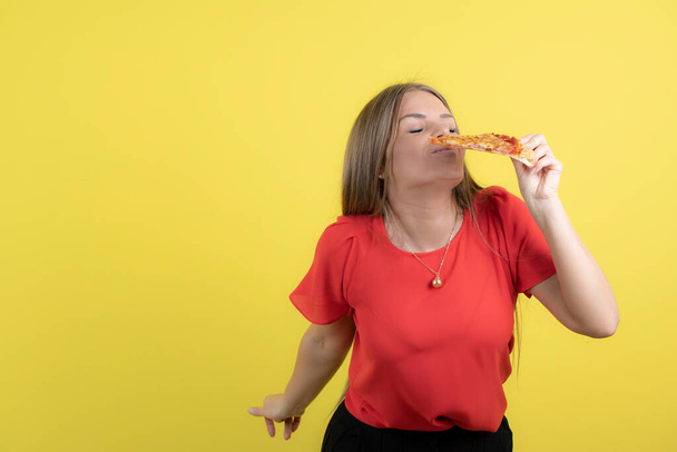 Lezzetli bir dilim pizza yiyen çekici bir kadın görüntüsü. Yüksek kalite fotoğraf - Fotoğraf, Görsel