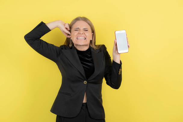 Изображение молодой красивой деловой женщины, показывающей свой телефон и страдающей головной болью. Высокое качество фото - Фото, изображение