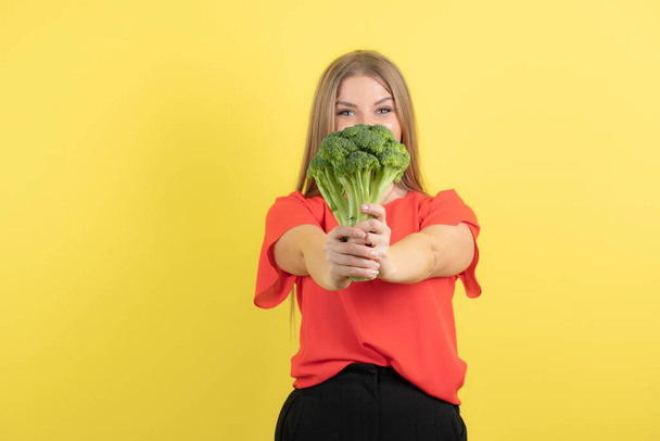 Afbeelding van mooie vrouw model tonen broccoli naar camera. Hoge kwaliteit foto - Foto, afbeelding