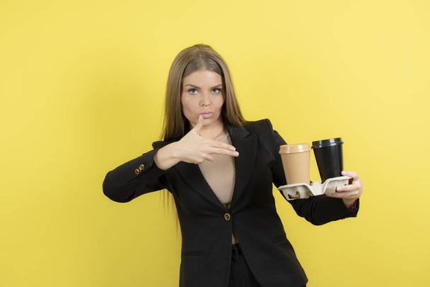 Obraz pięknej młodej kobiety trzymającej filiżanki kawy na żółtym tle. Wysokiej jakości zdjęcie - Zdjęcie, obraz