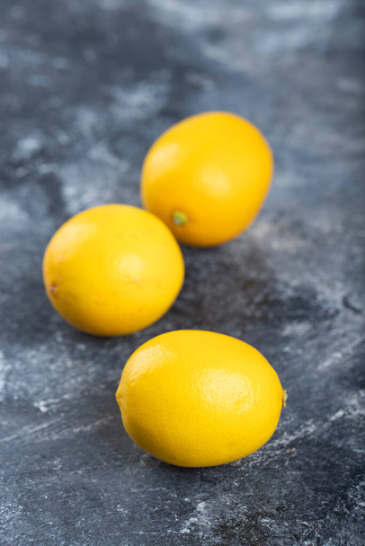 Drie sappige rijpe citroenen plaatsten een marmeren achtergrond. Hoge kwaliteit foto - Foto, afbeelding