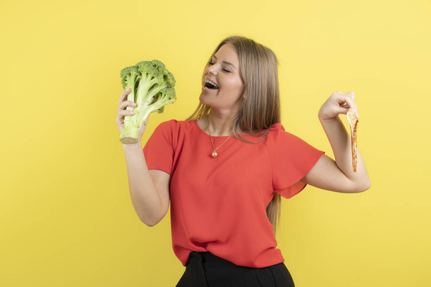 Kép gyönyörű nő modell kezében brokkoli és finom pizza. Kiváló minőségű fénykép - Fotó, kép