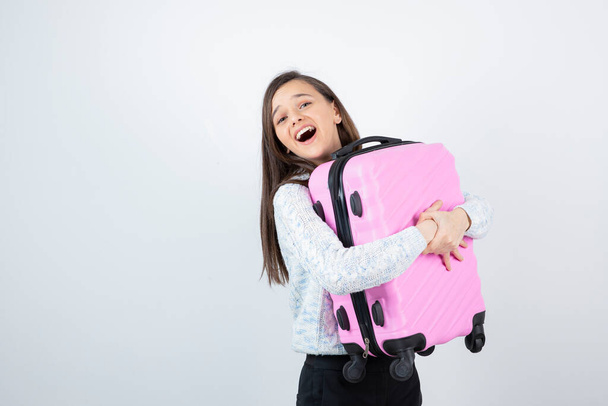 dívka na sobě svetr pózování s koly zavazadla na bílém pozadí - Fotografie, Obrázek