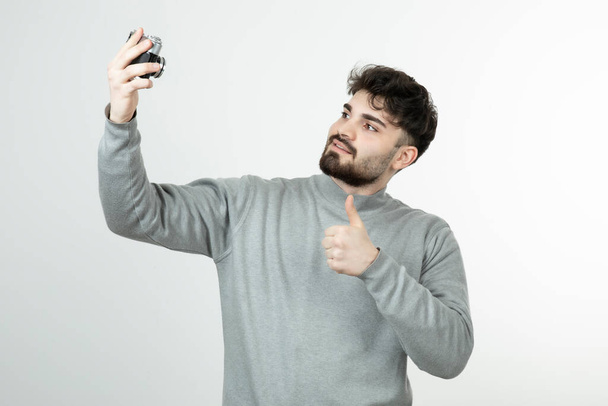 Portrait d'un bel homme prenant selfie avec caméra et montrant pouce vers le haut. Photo de haute qualité - Photo, image