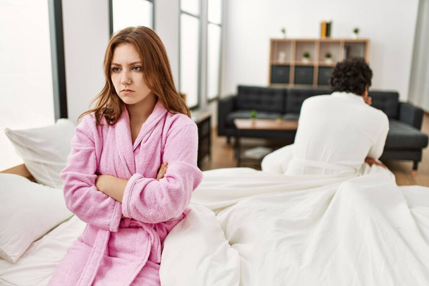 Young couple with serious expression on trouble sitting on the bed at bedroom. - Photo, Image