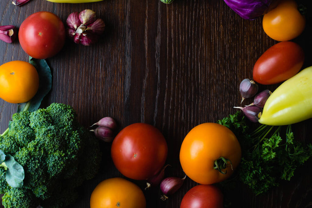 Concepto de vegetarianismo y nutrición adecuada. Vegetales tomates, ajo, calabacín, col, cilantro, pimientos en una mesa de madera oscura, vista superior, espacio de copia en el centro - Foto, imagen