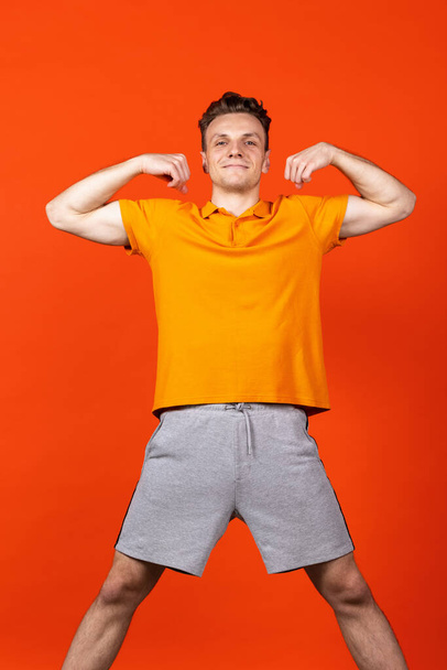 Portrait of young Caucasian man standing isolated on orange color studio background. Concept of human emotion, facial expressions, youth, feelings, ad. - Fotografie, Obrázek