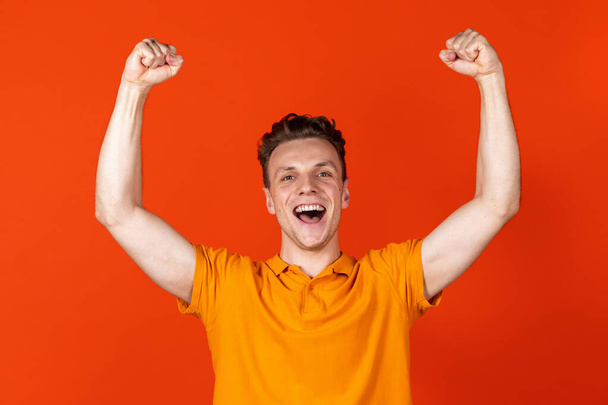 Portrait of young Caucasian man standing isolated on orange color studio background. Concept of human emotion, facial expressions, youth, feelings, ad. - Фото, зображення