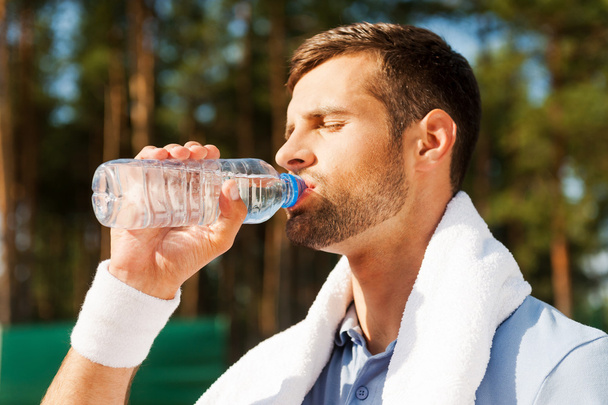 Young thirsty man drinking water - Fotó, kép