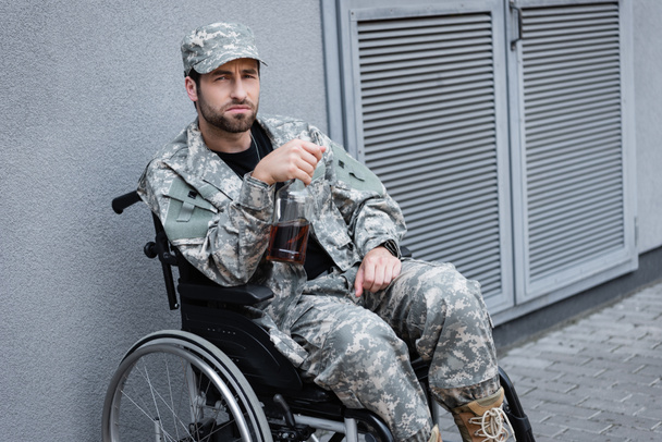 落ち込んで身体の不自由な軍人が酒を飲みながら車椅子に座り - 写真・画像