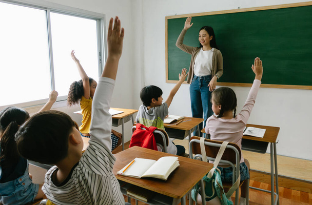 Grupa zróżnicowania dzieci w szkole podstawowej podnieść rękę do odpowiedzi na pytanie nauczyciela w klasie. Edukacja, szkoła podstawowa, nauka, Powrót do koncepcji szkoły - Zdjęcie, obraz