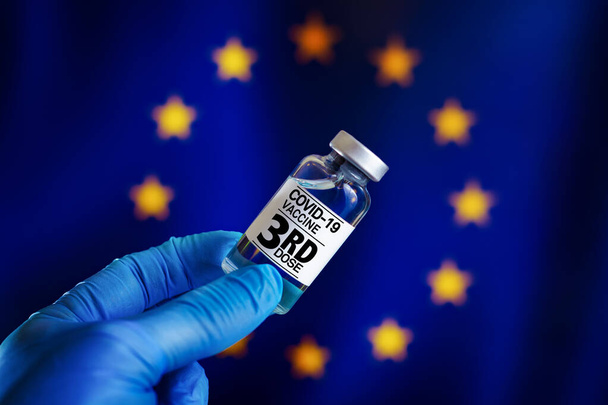 harmadik adag Covid-19 vakcina a veszélyeztetett populációs betegségekben oltott emlékeztető oltáshoz az EU országaiban. 3. adag vakcinát tartalmazó injekciós üveg kovid-19 vagy Coronavirus számára az Európai Gazdasági Közösség lobogója alatt - Fotó, kép