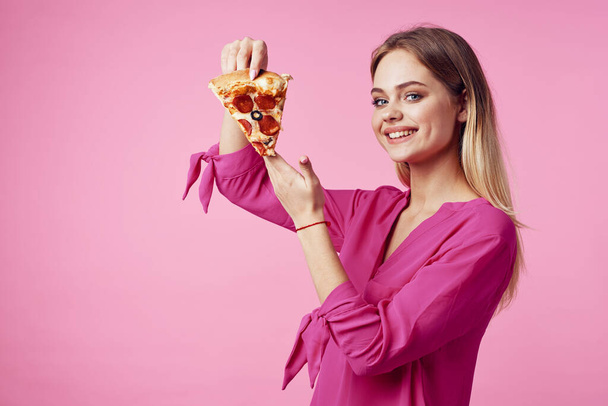 leuke vrolijke vrouw met pizza in handen op roze achtergrond. Hoge kwaliteit foto - Foto, afbeelding