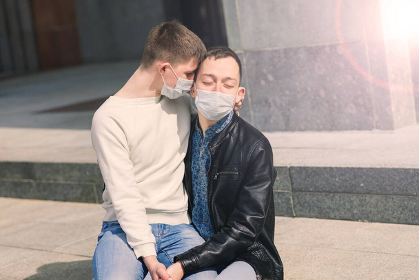 Young gay couple wearing medical mask hugging at the city. - Foto, Imagen