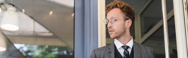 businessman in glasses and classy suit looking away near cafe entrance, banner - Foto, Imagem