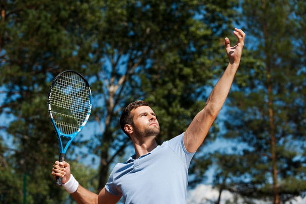 Confident male tennis player serving ball - Fotó, kép