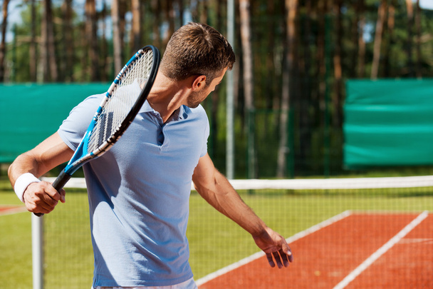 Young man playing tennis on court - Fotó, kép