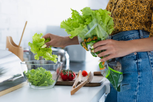 Cropped view of african american woman holding lettuce while cooking salad  - Foto, Imagem