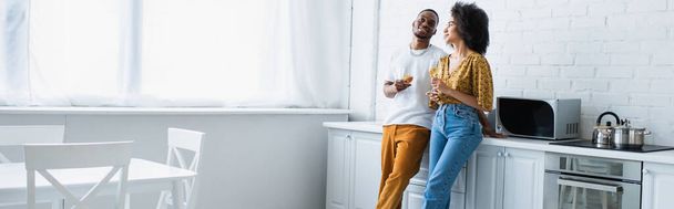 Afrikai amerikai férfi kezében bor közelében barátnője a konyhában, banner  - Fotó, kép