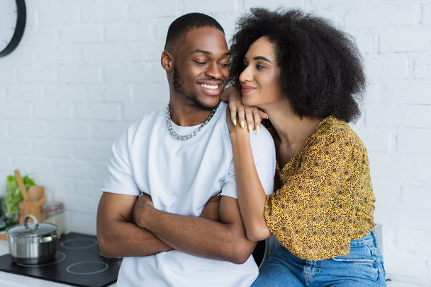 Young african american woman hugging smiling boyfriend at home  - Photo, Image