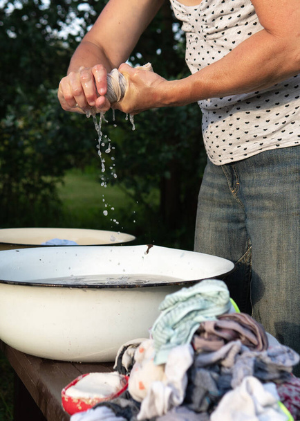 Žena balí spodní prádlo do starého umyvadla venku v létě - Fotografie, Obrázek
