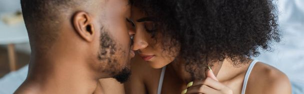 Afro-Amerikalı bir adam yatak odasında kız arkadaşını öpüyor.  - Fotoğraf, Görsel
