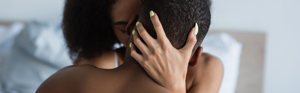 Young african american woman kissing shirtless boyfriend on bedroom, banner  - Fotografie, Obrázek